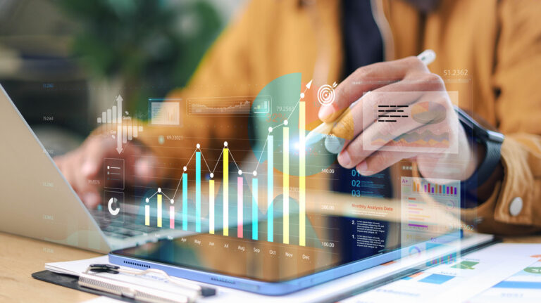 Business data analysis on tablet and laptop with financial charts, KPI metrics, and dashboard interface for strategy planning and performance tracking.