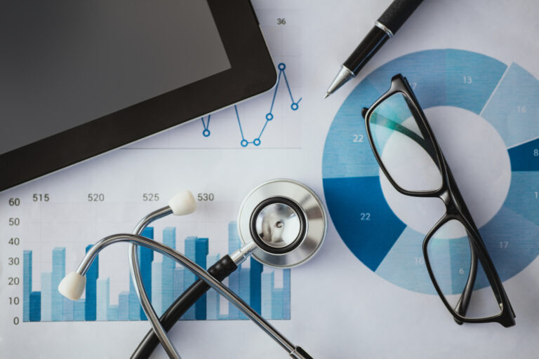 Glasses, a tablet computer, and a stethoscope sitting on top of printed out reports