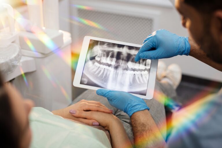 Dentist reviewing a dental X-ray with a patient using a tablet, highlighting modern dental care.